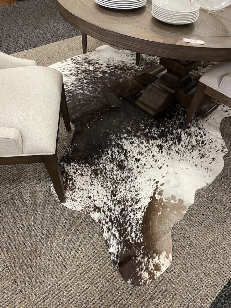 Black and white cowhide rug under a dining table