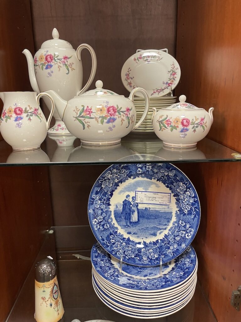 Floral china tea set and blue transferware plates in a display cabinet